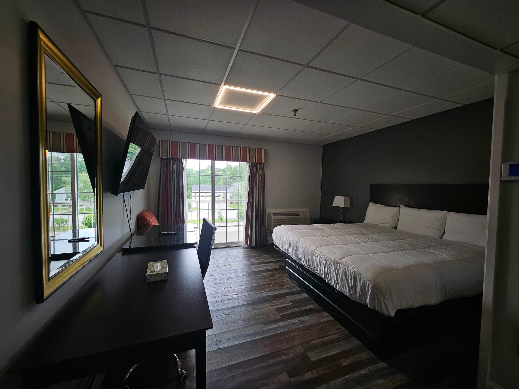 Saffron Inn king balcony room — one king bed with white linens, dark wood headboard, large gold-framed mirror, desk by sliding glass door looking onto the balcony
