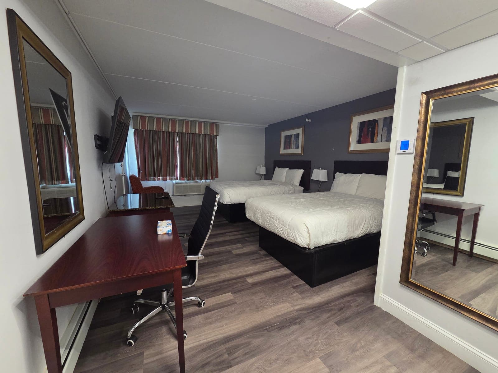 Saffron Inn two-double ground-floor room — alternate angle with curtains drawn, soft daylight on the wood floor